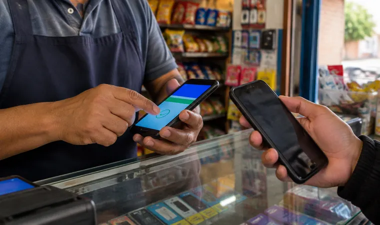 Tendero vendiendo una recarga de celular a un cliente
